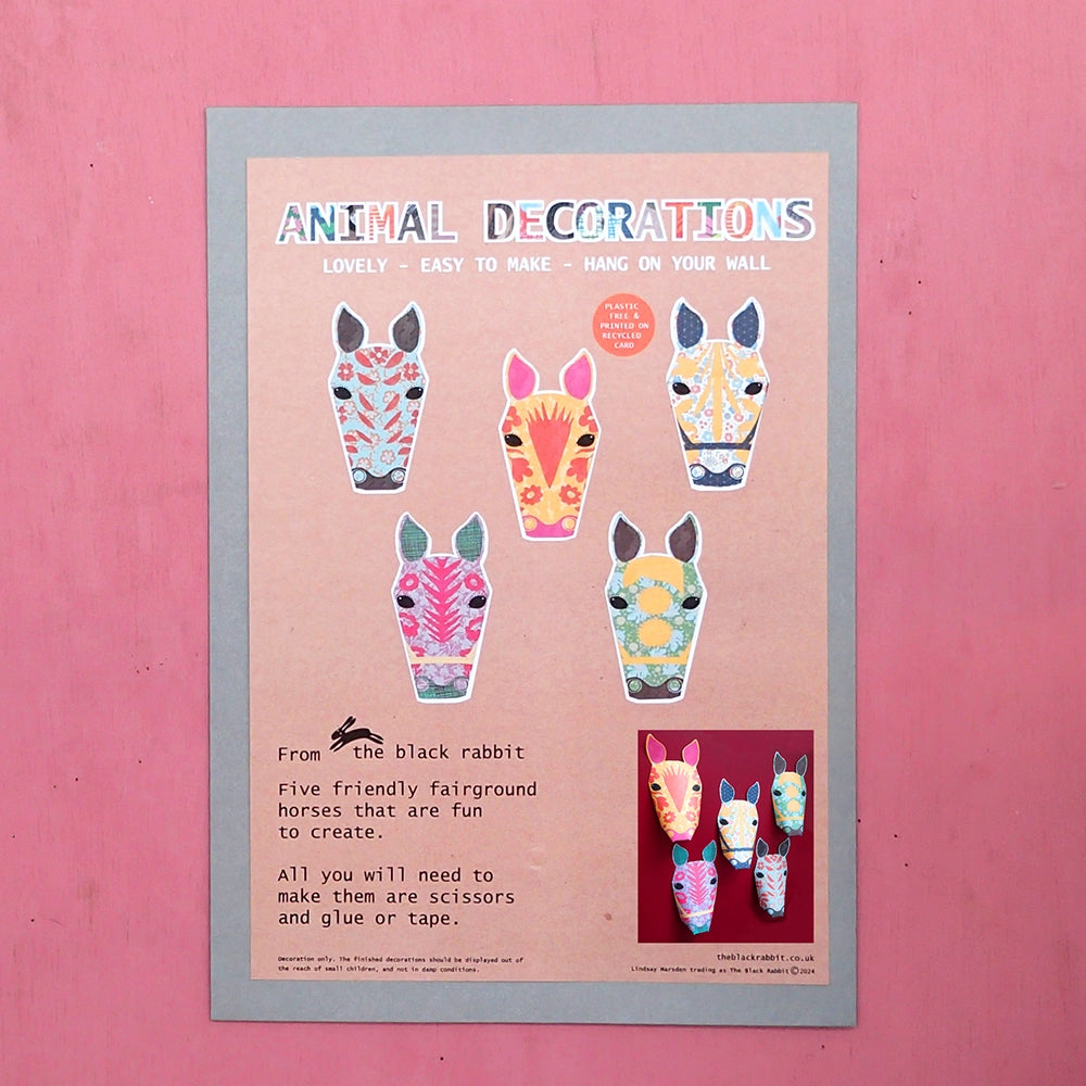 Carousel horse paper kit packaging featuring images of five fairground horse decorations on pink background