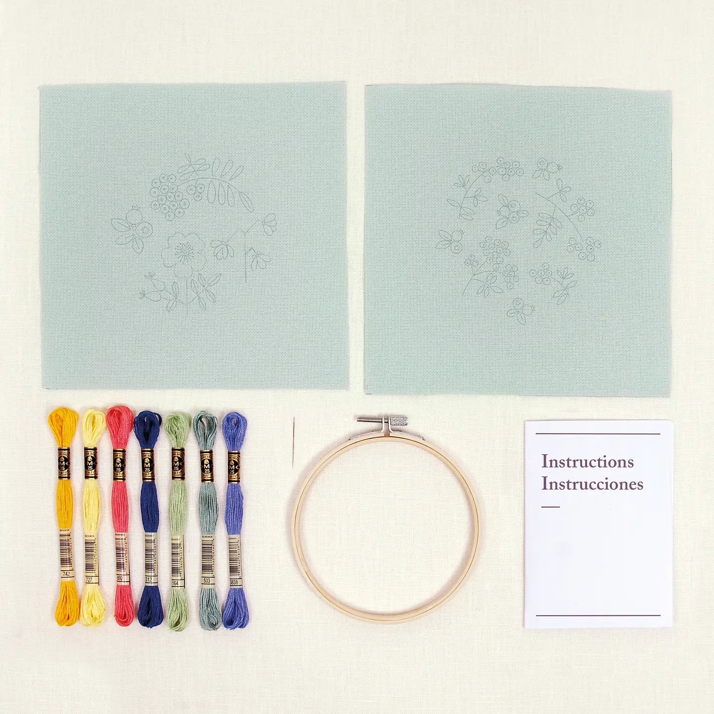 Embroidery kit with printed designs, threads, hoop, and instructions on a light background