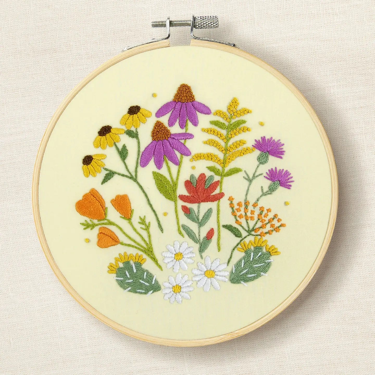 Embroidery hoop with colourful floral design on a cream background