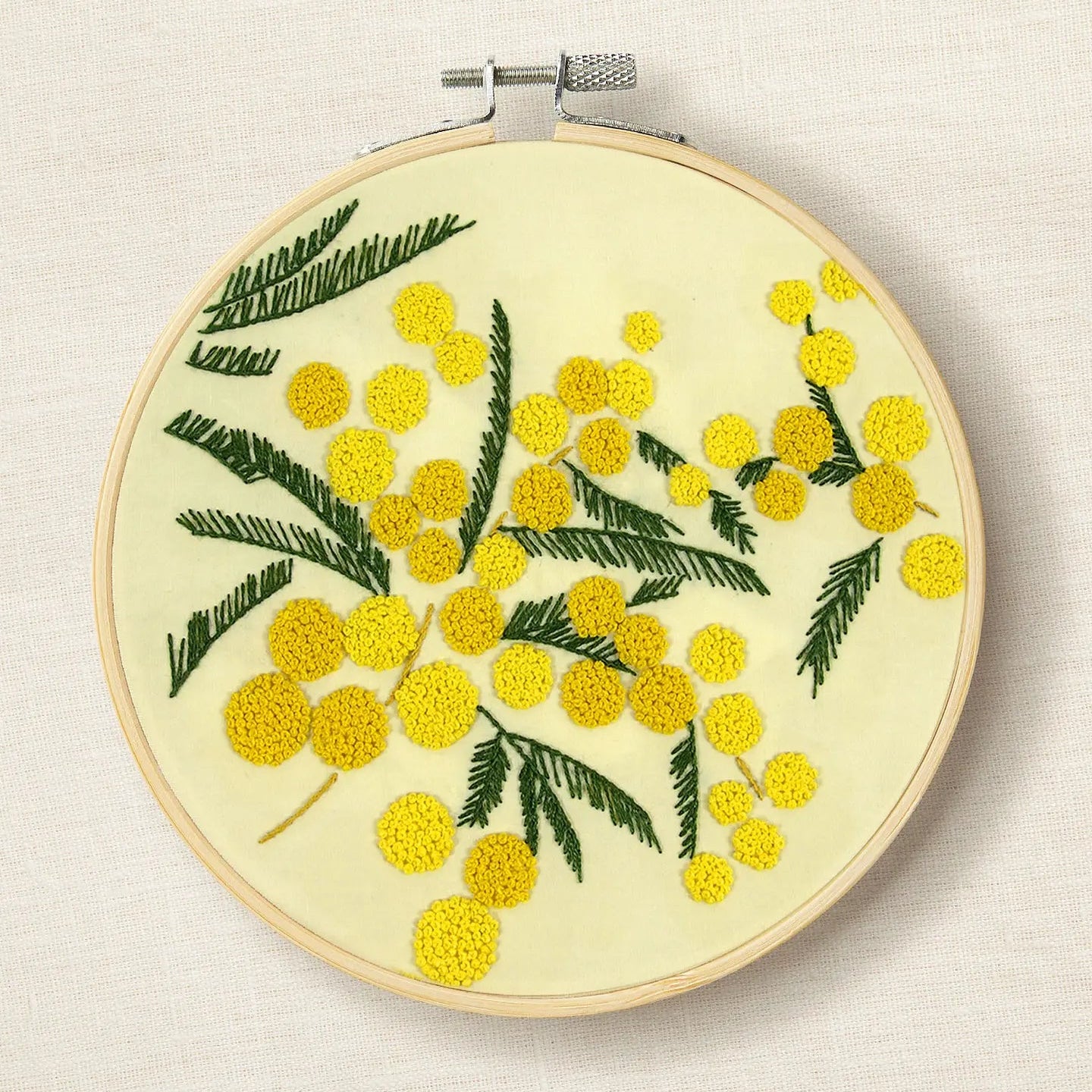 Embroidery hoop with yellow floral design on a beige background