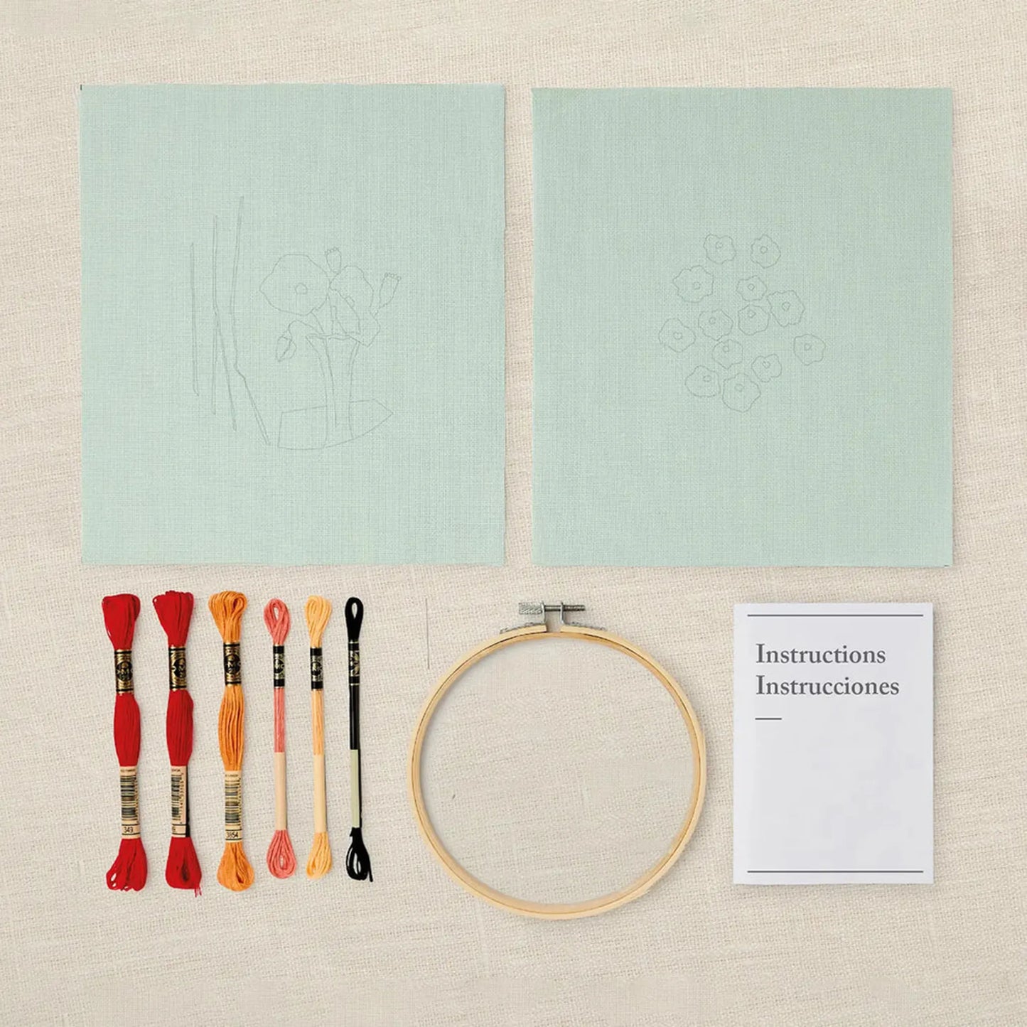 Poppies embroidery kit with threads, hoop, and instructions on a cream background