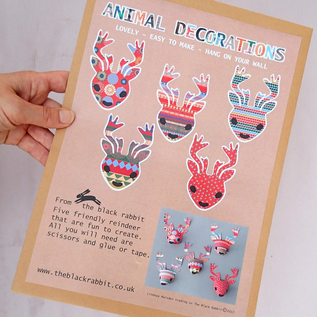Close-up of person holding reindeer decorations paper kit package with illustrations of contents