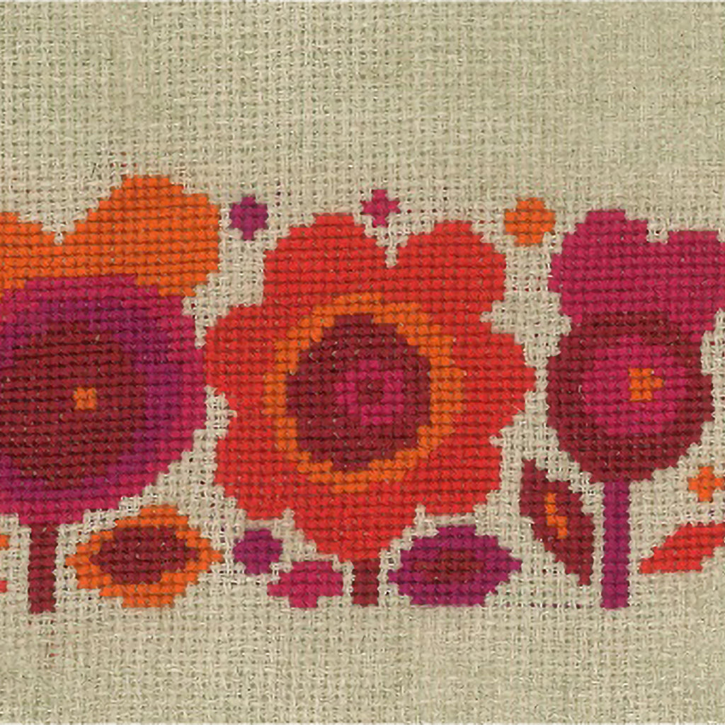Retro 1970s-style cross stitch flowers in red, orange, and pink on natural coloured counted linen