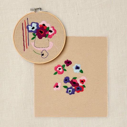 Completed floral embroidery in hoop with a coordinating botanical design on natural fabric