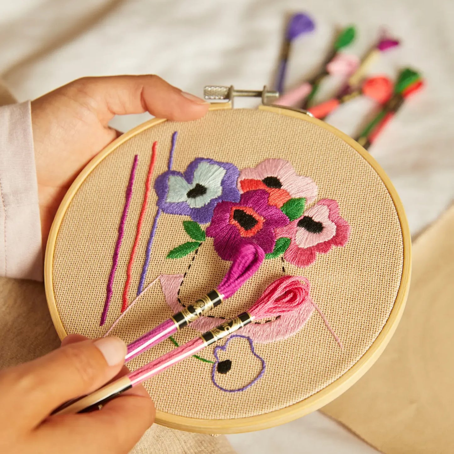 Person holding anemone embroidery in hoop with coordinating embroidery threads