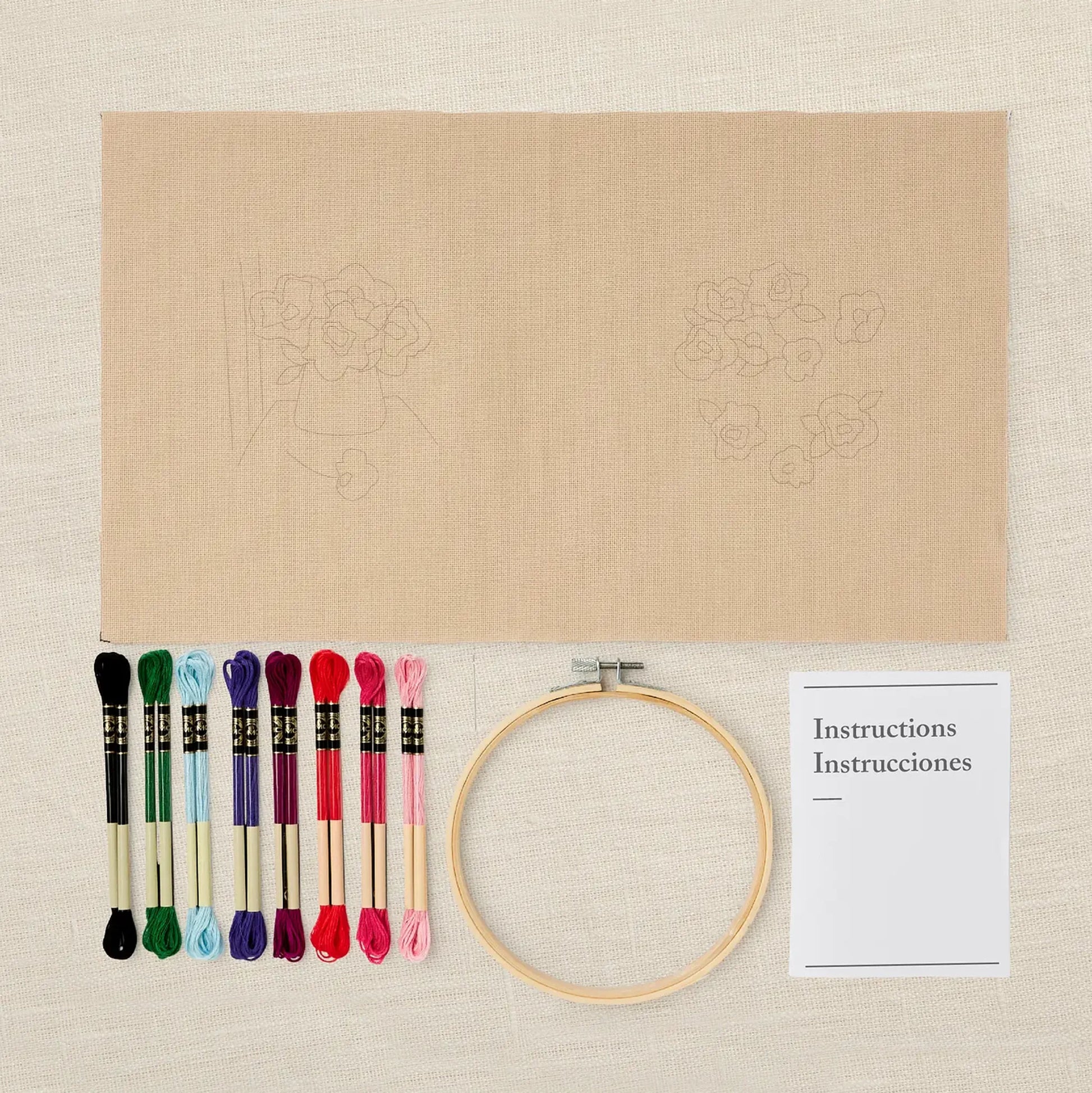 Anemone embroidery kit with threads, hoop, and instructions on a natural fabric background
