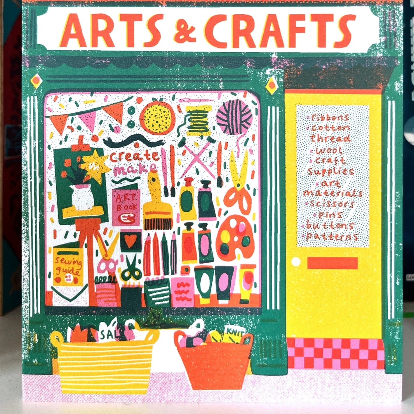 Clowe up of illustrated note card featuring a colourful arts and crafts shop front with a window full of supplies