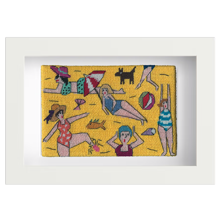 Needlepoint postcard of women in brightly coloured bathing costumes, hats, and caps on a yellow beach background, framed in white