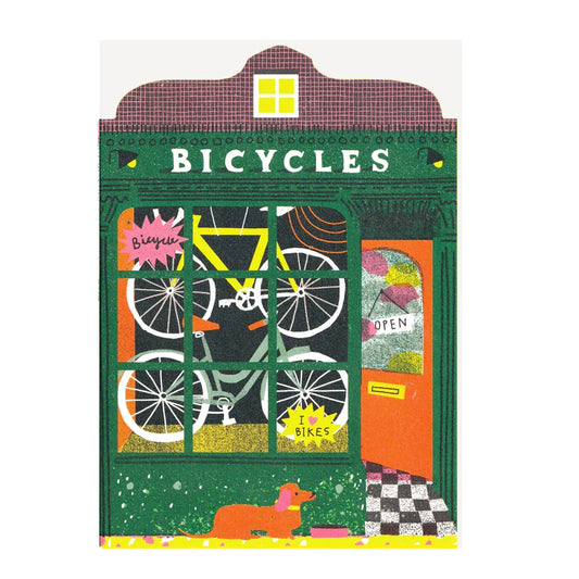 Illustrated note card featuring Bicycles shop front with bicycles hanging in the window, an open door and a dog in front, set against a white background