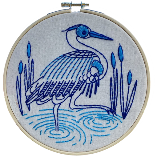 Embroidery hoop with completed blue heron embroidered design on white fabric