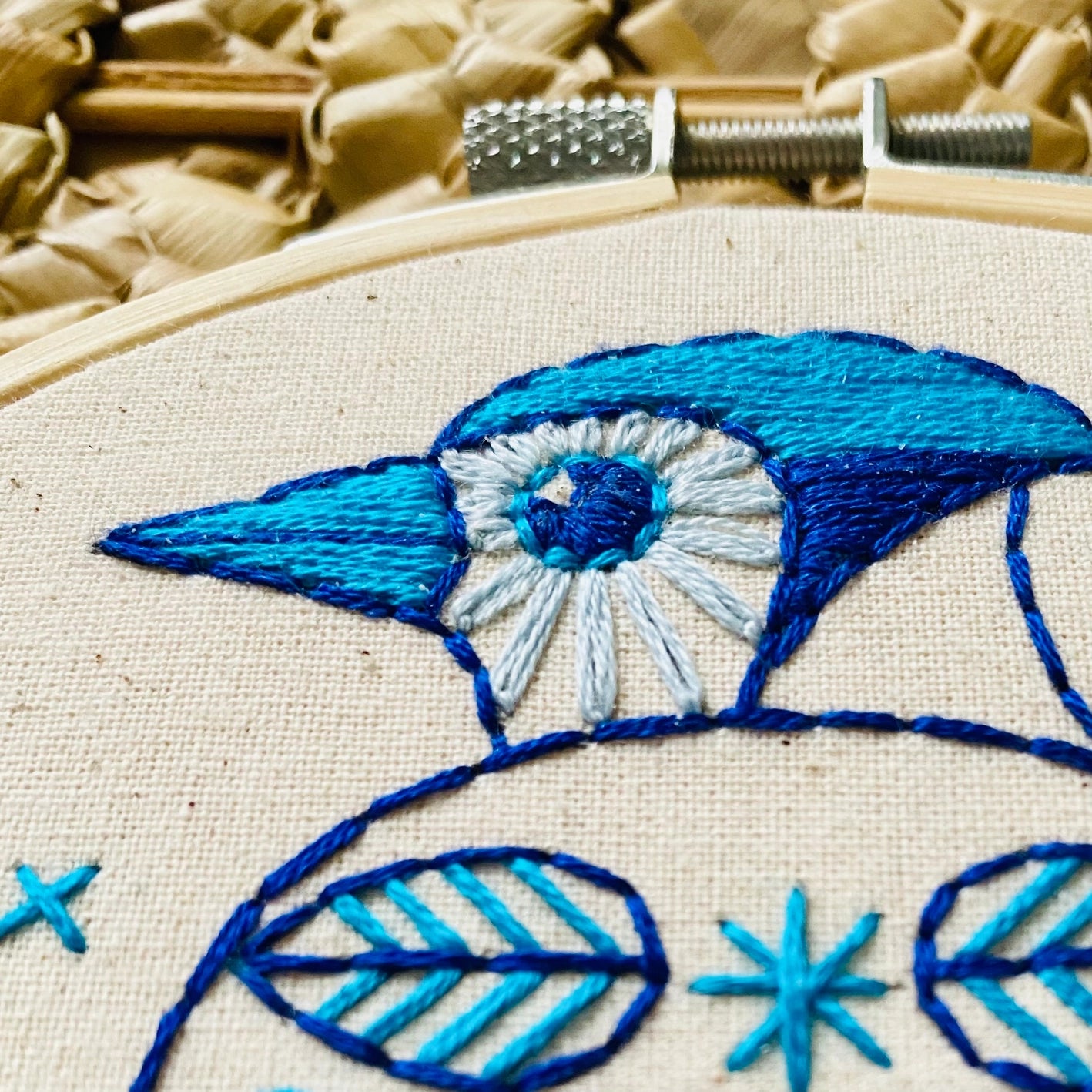 Close-up of blue jay embroidery showing stitch detail, in wooden embroidery hoop