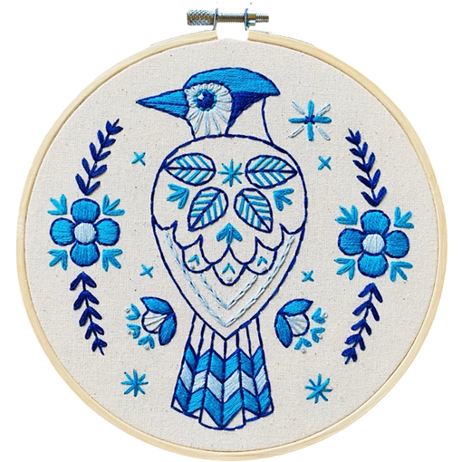 Embroidery hoop with blue bird design and floral patterns on white fabric, the blue jay embroidery kit