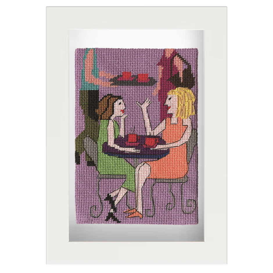 Framed needlepoint of two women at a café table with a purple background