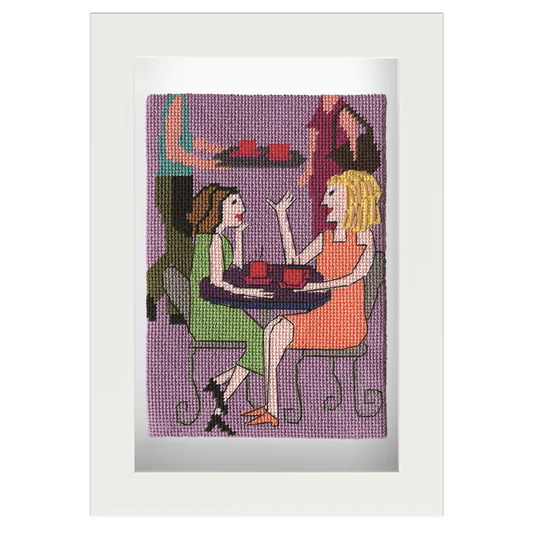 Framed needlepoint of two women at a café table with a purple background