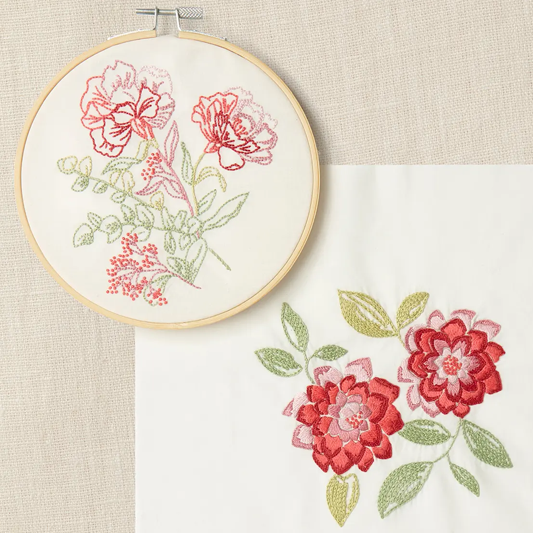 Embroidery hoop featuring red and pink carnation flowers with a coordinating design on a cream background
