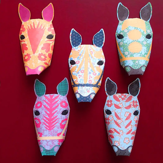 A set of five colourful, patterned carousel horse decorations made from paper, displayed against a dark red background