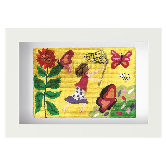 Needlepoint postcard of a woman running in a colourful garden with a butterfly net, on a yellow background, framed in white