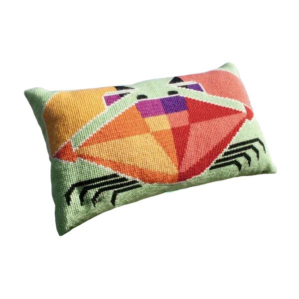 Cross stitch cushion with a bold red and orange geometric crab design on a pale green background