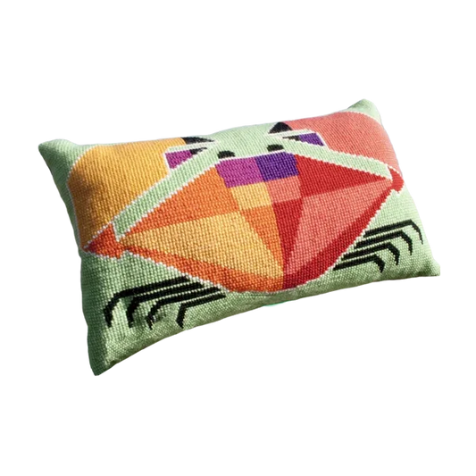 Cross stitch cushion with a bold red and orange geometric crab design on a pale green background