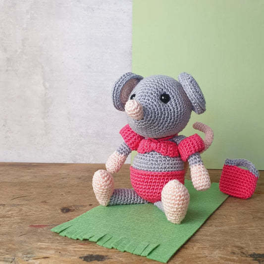 Crocheted mouse toy wearing a pink bikini  and armbands sitting on a green mat