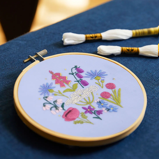 Embroidery hoop with floral design on a blue fabric background