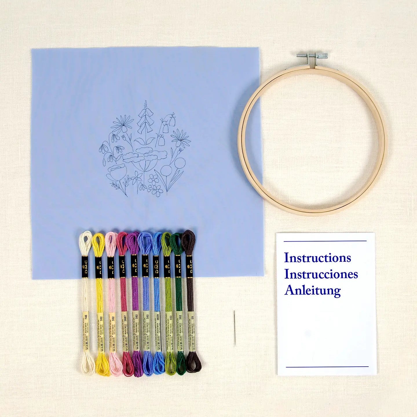 Embroidery hoop, printed design on fabric, colourful thread, and instructions on a cream background