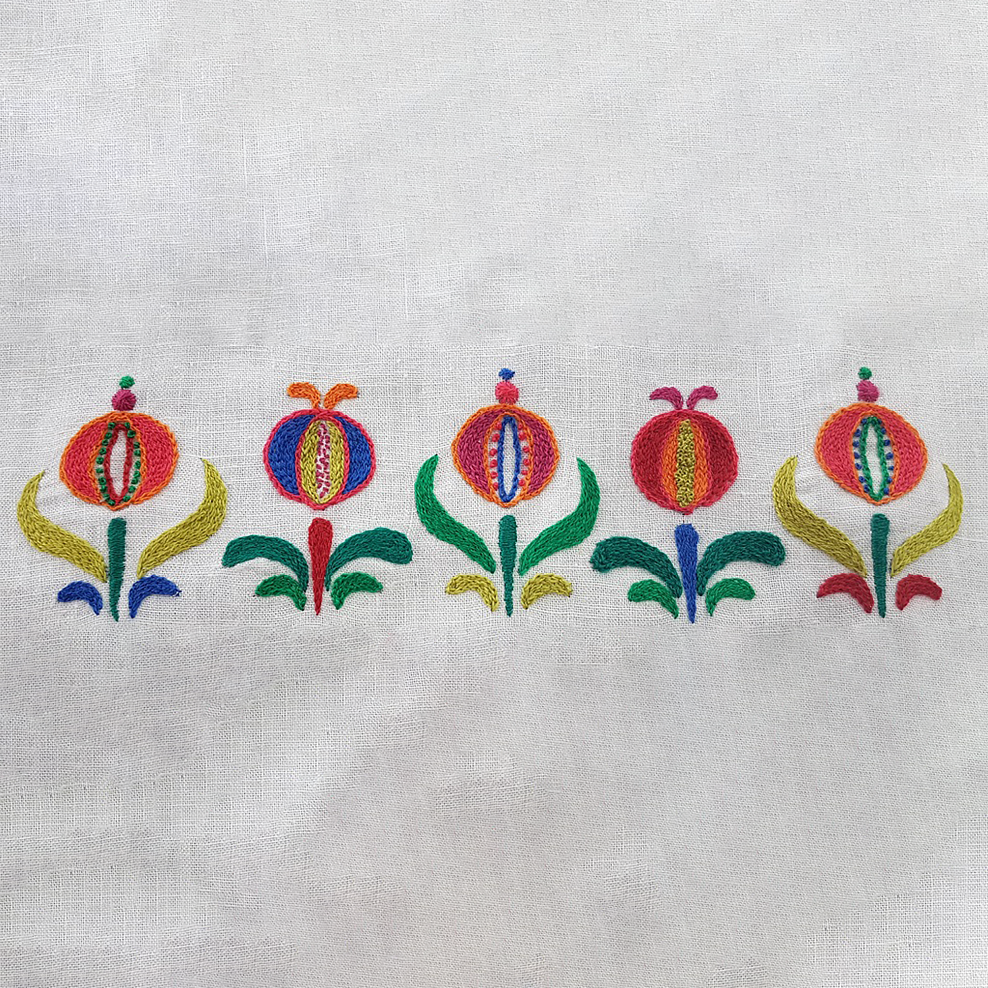 Embroidered pomegranate floral design on an off-white fabric background