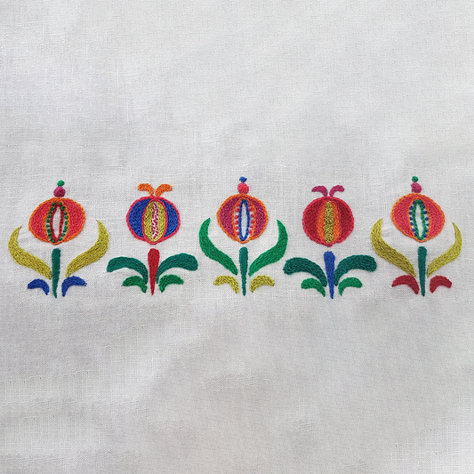 Embroidered pomegranate floral design on an off-white fabric background