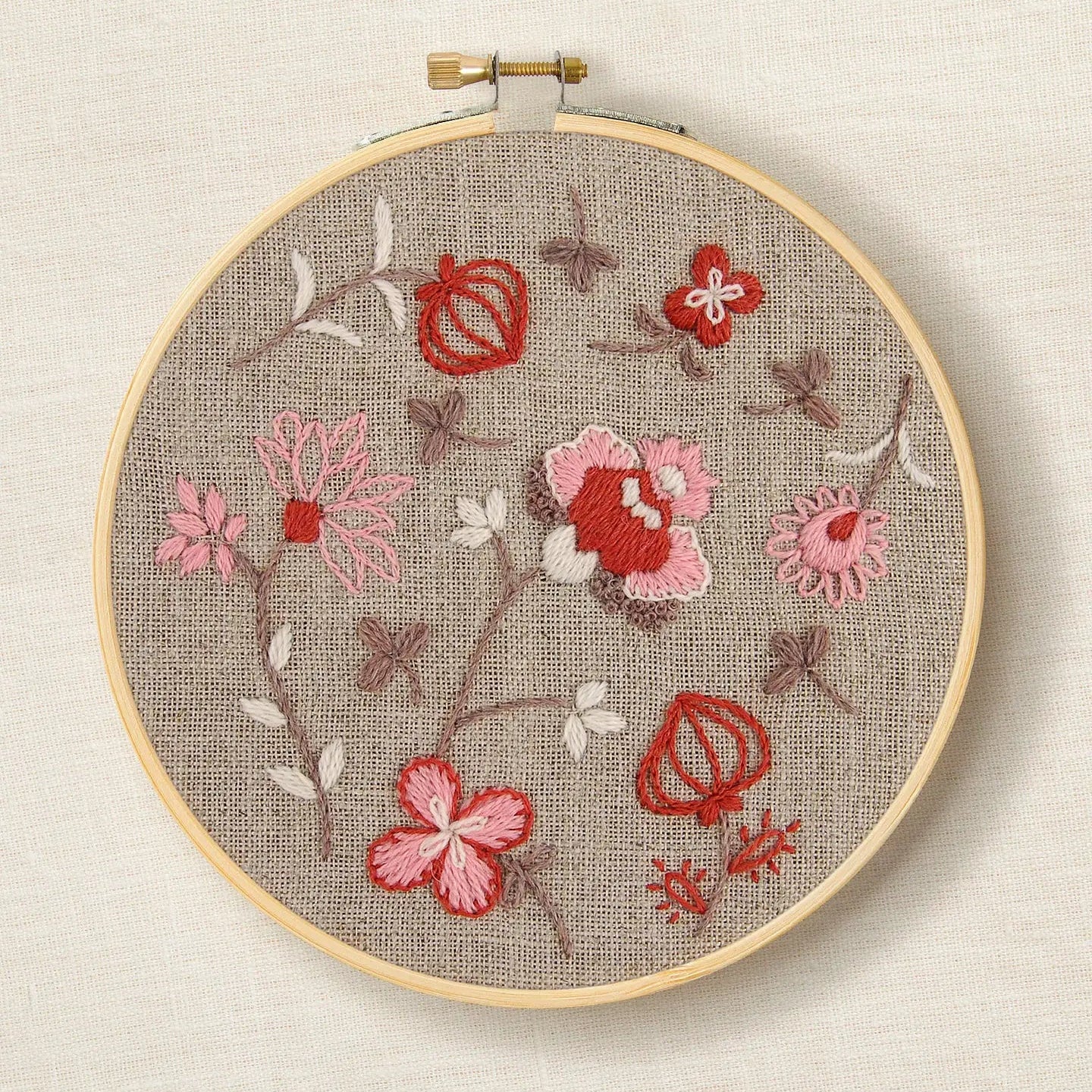 Indian Botanical embroidery hoop with completed floral design in warm earthy tones on linen fabric
