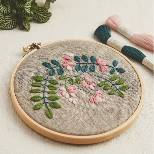 Indigo Botanical embroidery hoop with indigo-inspired botanical motifs stitched in pink and green tones on natural linen fabric