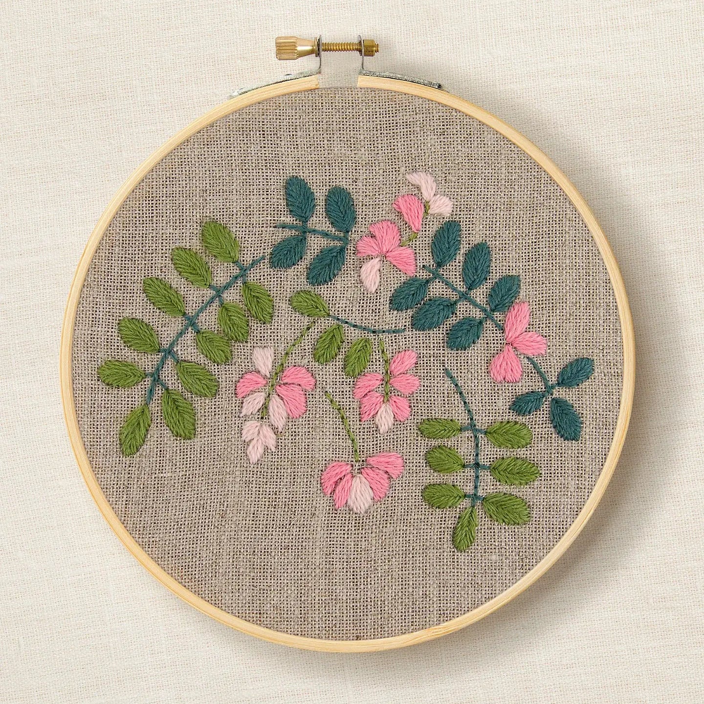 Embroidery hoop with stitched Indigo botanical design on a natural linen background