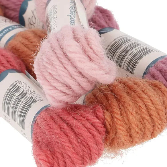 Close-up of pink, orange, and purple yarn with labels on a white background