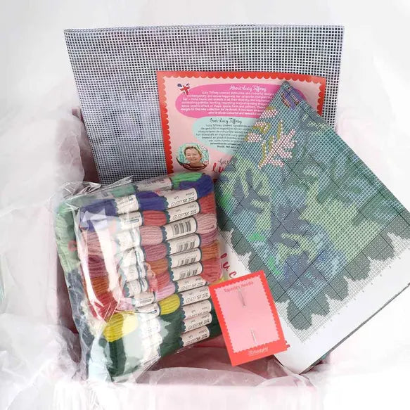 Needlepoint kit with fabric, threads, and patterns on a white background