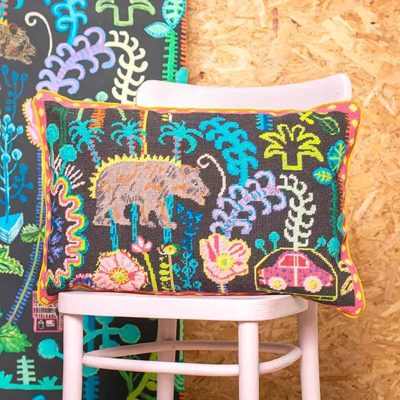 Decorative needlepoint cushion with colourful patterns on a chair against a wooden wall