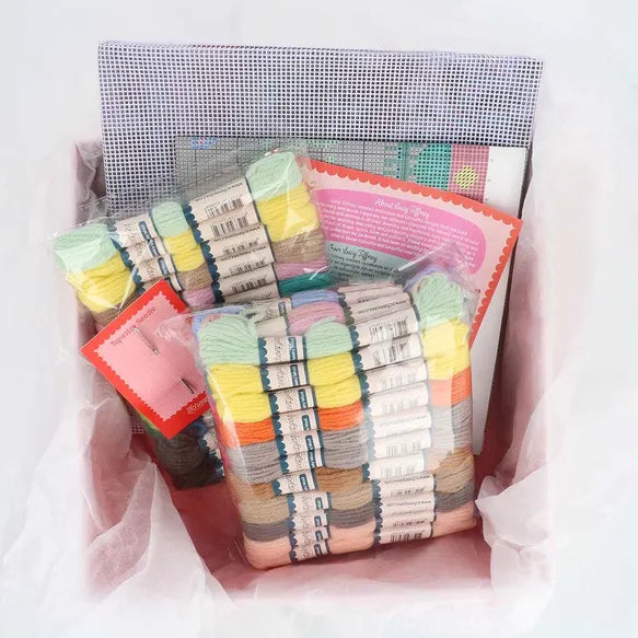 Packaged colourful yarn with a pink label on a white background