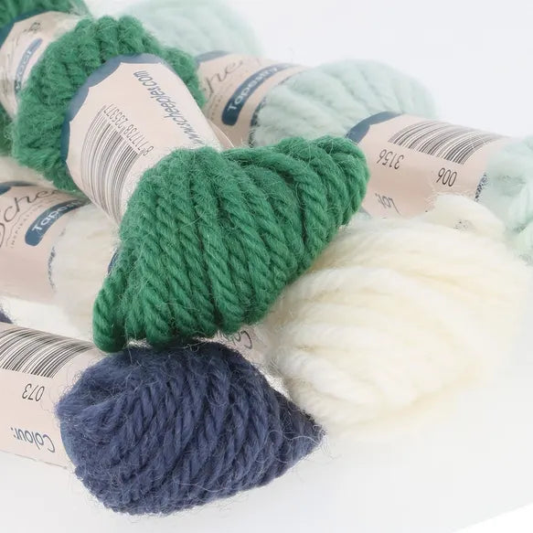 Green, white, and blue yarn skeins on a light background
