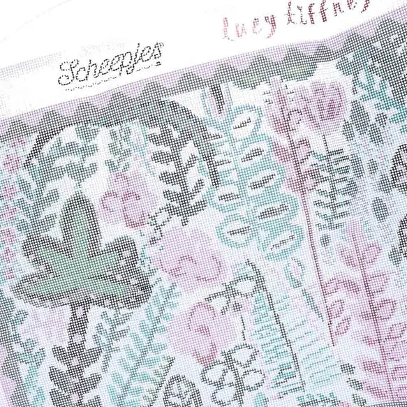 Close-up of a needlepoint canvas with floral designs and visible Lucy Tiffney and Scheepjes branding