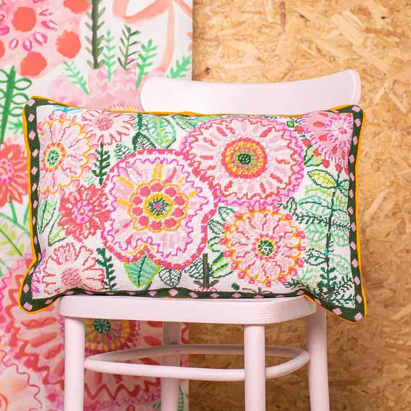 Colourful floral cushion on a pink chair with a wooden wall background
