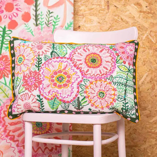 Colourful floral cushion on a pink chair with a wooden wall background