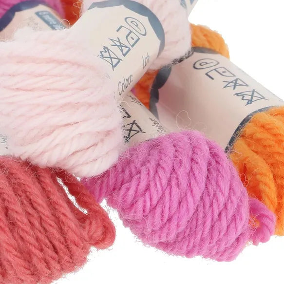 Close-up of colourful yarn skeins in pinks, and orange with labels on a white background