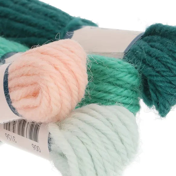 Close-up of yarn skeins in green, pink, and white on a white background