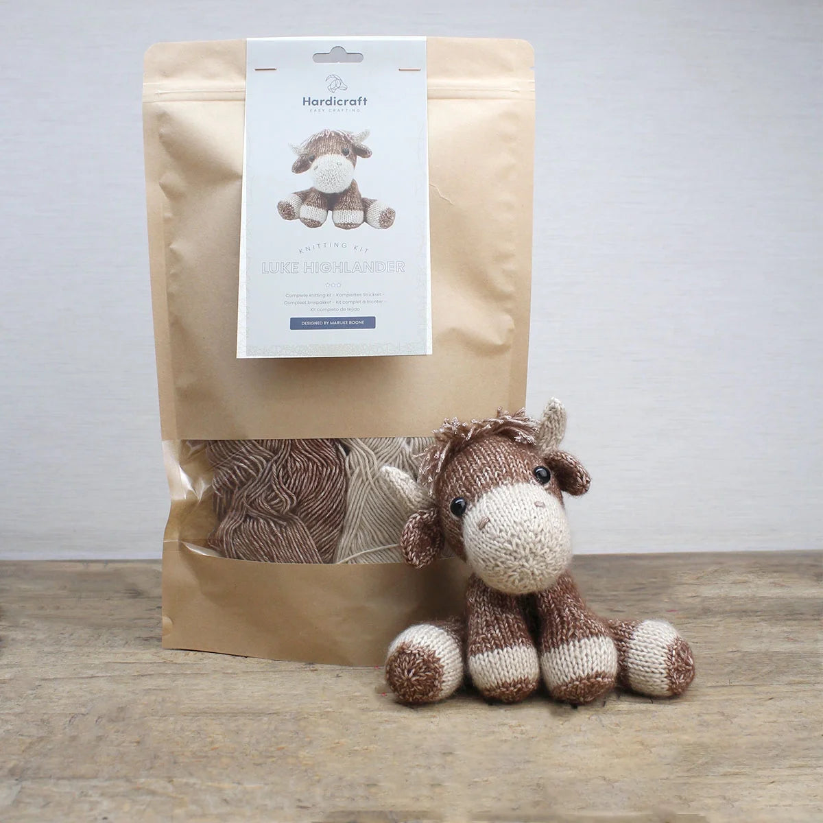 Highland cow knitting kit in simple kraft packaging with yarn and finished soft toy