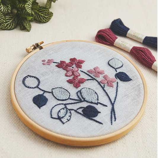 Lunaria Botanical embroidery hoop with stitched lunaria flowers and seed pods on pale linen fabric