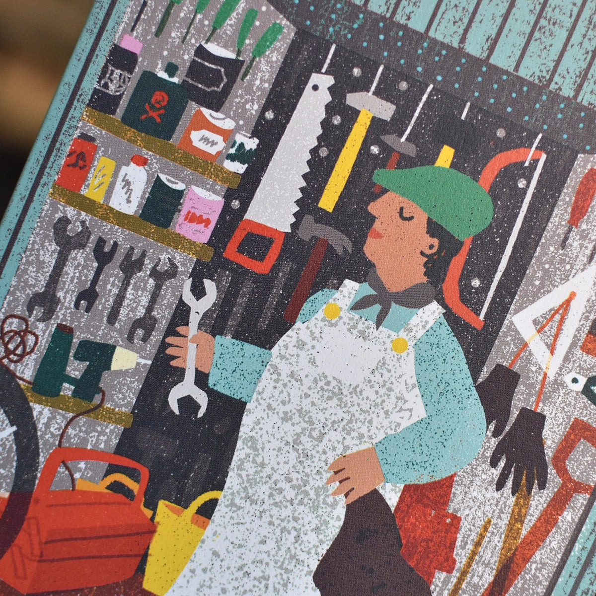 Close-up of an illustrated note card featuring a man wearing white overalls and a blue shirt in a shed full of different brightly coloured tools