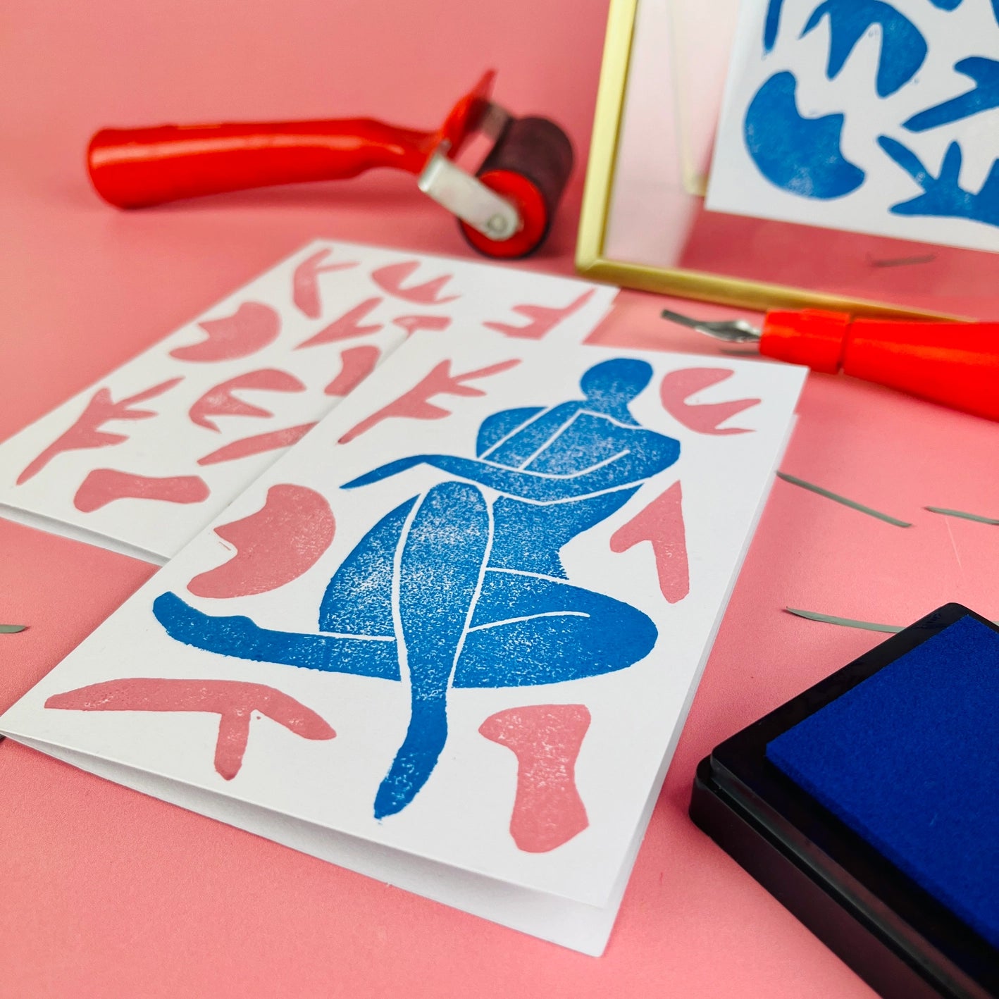 Matisse-inspired lino print card in shades of blue and pink with print tools in background