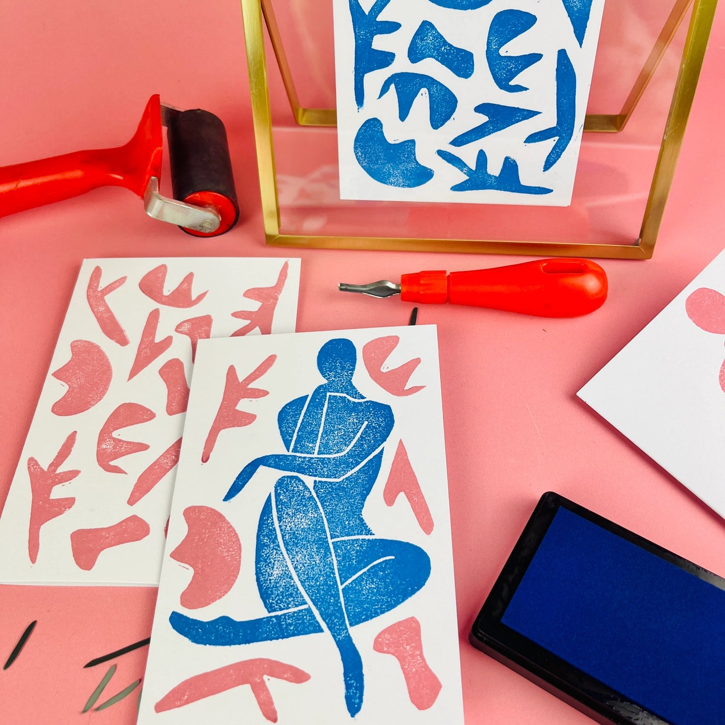 Matisse-inspired lino print cards in shades of blue and pink with gold framed picture and print tools in background