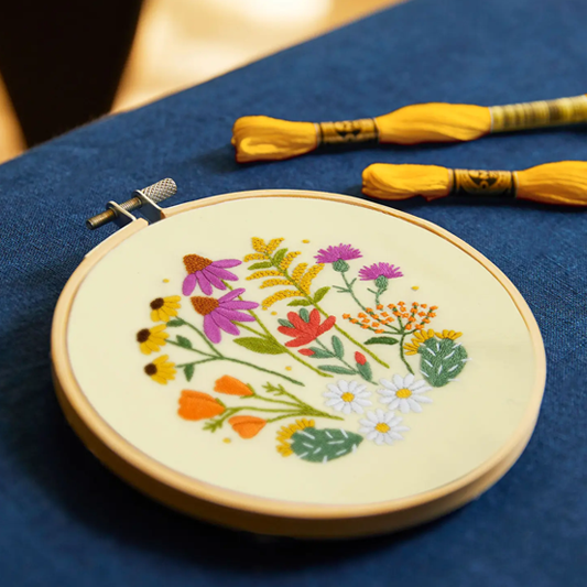 Embroidery hoop with floral design on a blue fabric background