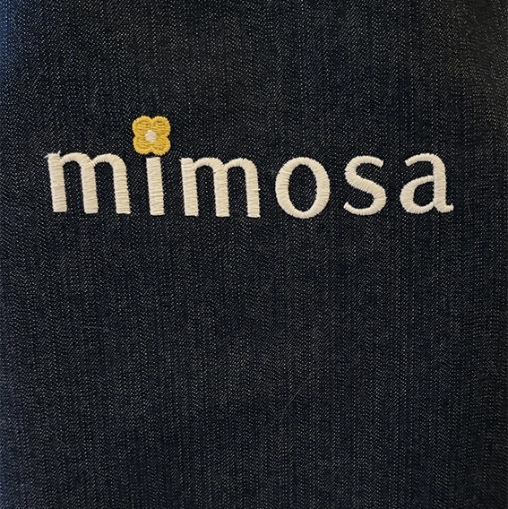 Close up Mimosa denim apron showing embroidered logo detail