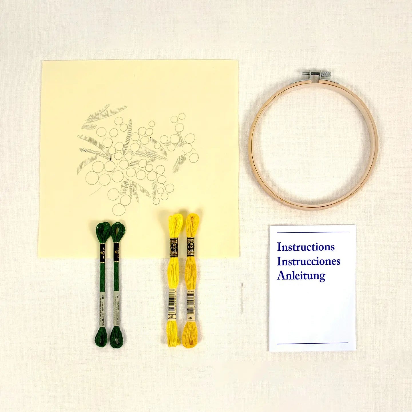 Embroidery kit featuring printed design on fabric, hoop, thread, and instructions on a cream background