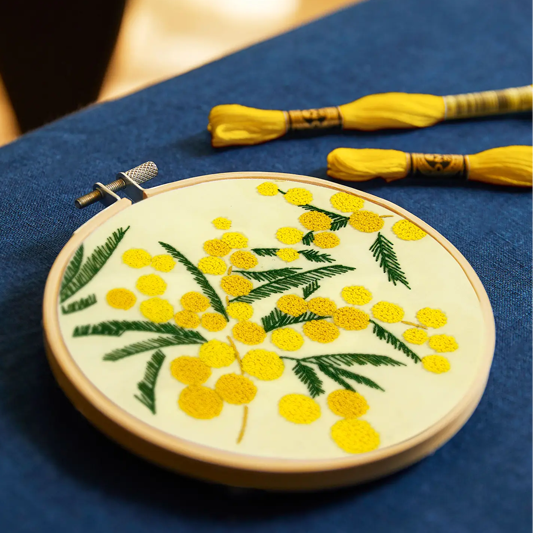 Embroidery hoop with yellow floral design on a blue fabric background